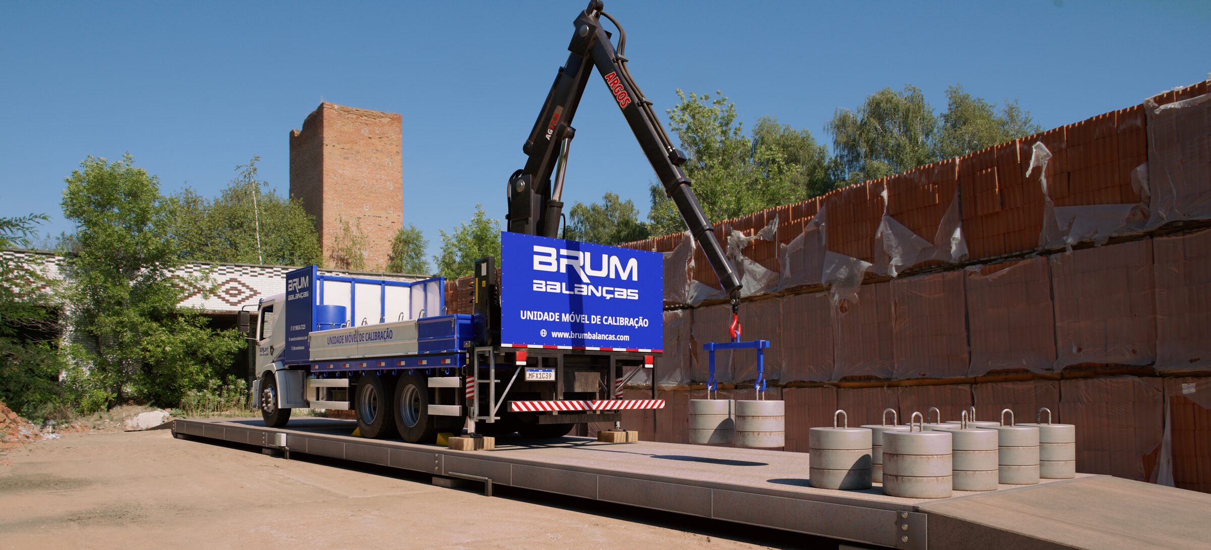 Unidade móvel de calibração da Brum, um VW Constellation com guindaste ARGOS, parada sobre a plataforma de uma balança rodoviária no pátio de uma olaria. O guindaste desce dois pesos-padrão de 500 kg num balancim azul, e outros oito já estão na plataforma.